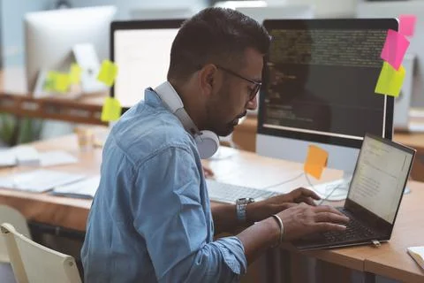 Software developer coding on laptop in modern office, focused on project Foto stock