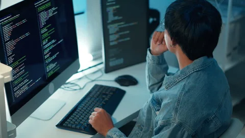 Software developer coding on multiple monitors focused on programming workflow Stock Footage 313820887