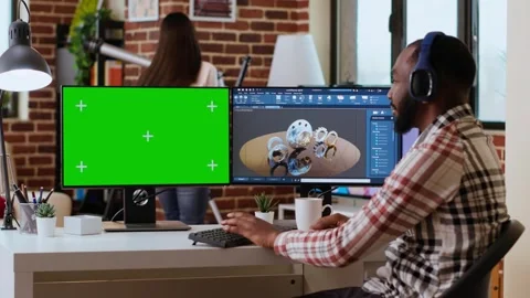 Software developer creates a gear prototype on dual monitors next to chroma key Stock Footage 319714933