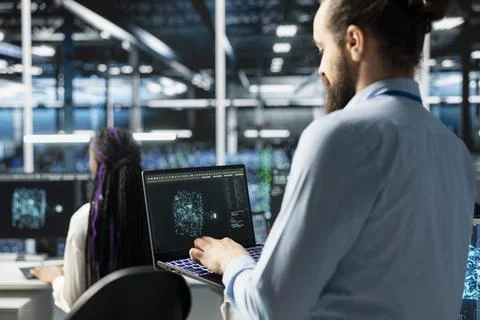 Software developer in data center using AI LLM assistant on laptop 写真素材