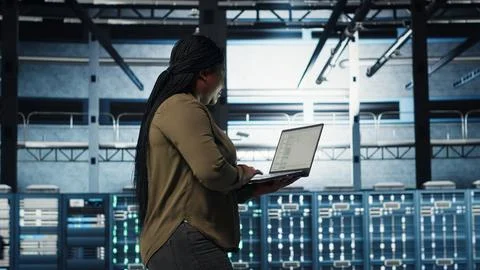 Software developer in data center using laptop to deploy new server architecture Foto stock