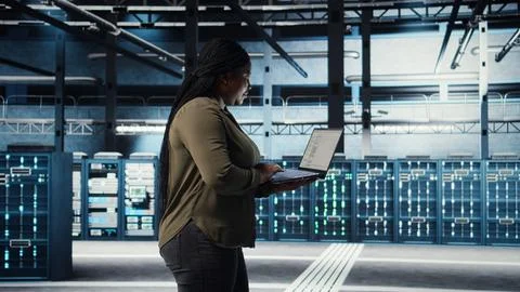 Software developer in data center using laptop to deploy new server architecture Stock Photos