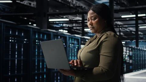 Software developer in data center using laptop to upgrade systems Stock Photos