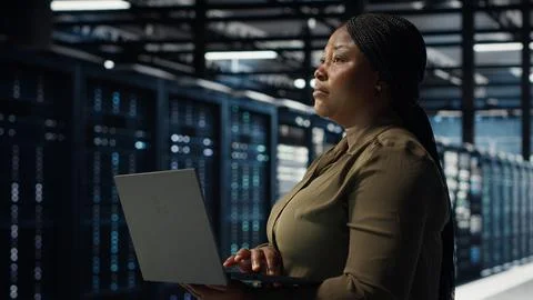 Software developer in data center using laptop to upgrade systems Foto stock