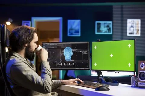 Software developer drinking coffee, watching AI on green screen PC Stock Photos