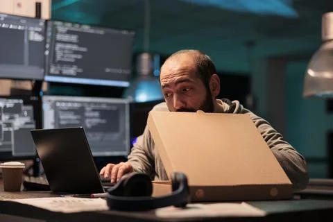 Software developer eating pizza from takeaway 写真素材