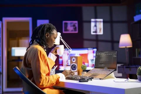 Software developer enjoying cup of coffee and writing code on laptop Stock Photos
