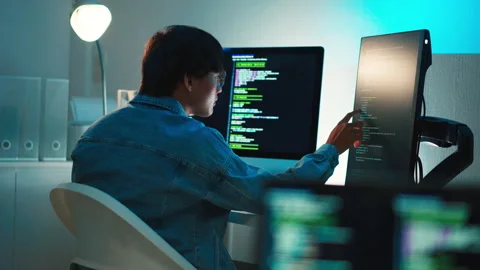 Software developer focused on debugging code with multi screen setup working on Stock Footage 313821001