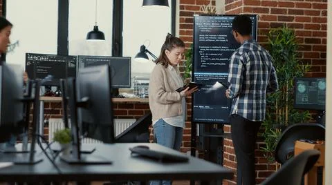 Software developer holding digital tablet analyzing code on wall screen tv Stock Photos