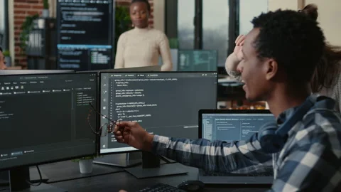 Software developer looking at running code on multiple screens takes off glasses Stock Footage 168236609