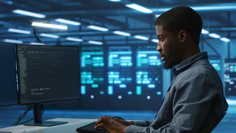 Software developer programming in high tech facility with server rows Stock Footage 276139168