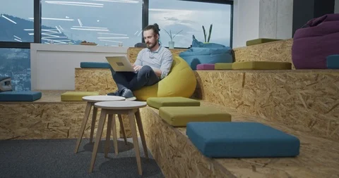 Software developer programming on laptop computer while sitting on lazy bag i Stock Footage 114045702