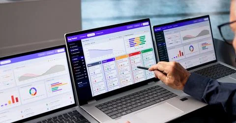Software Developer Reviews Bug Tracking Dashboard On Laptop During Sprint. Stock Photos