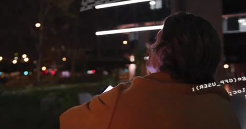 Software developer sitting bench night plaza inspecting emerging AR code overlay Stock Footage 309761789