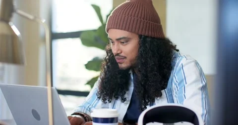 Software developer surveying laptop screen typing code to focus while sipping Stock Footage 337224558