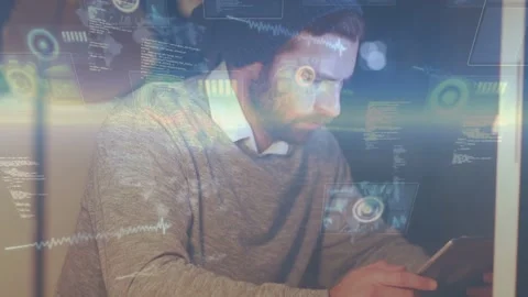 Software developer tapping tablet at desk, leaning in and analyzing code 動画素材 333903211