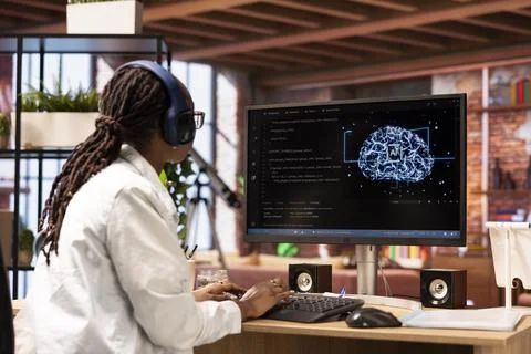 Software developer typing on PC keyboard, wearing headphones, using AI Stock Photos