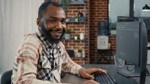 Software developer typing programming code on computer keyboard turning head and Stock Photos
