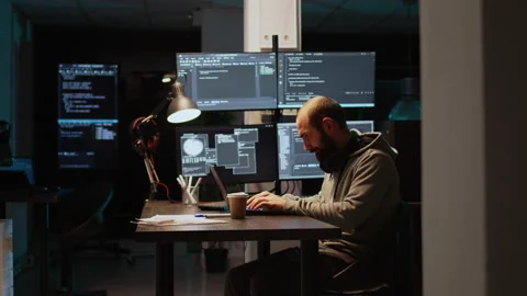 Software developer typing source code on laptop and multiple monitors Stock Footage 224582561