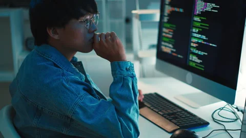 Software developer using keyboard focused on debugging programming code on dual Stock Footage 313813624