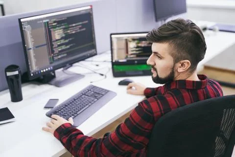 Software developer working on computer in IT office, sitting at desk and coding Stock Photos