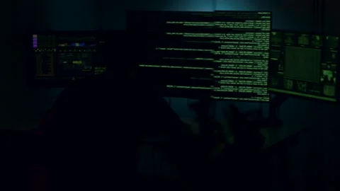 Software developer working late at night in a dark room, illuminated by multiple Stock Footage 314270607