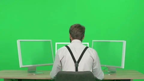Software developer working on a PC while sitting at a desk, green background, a Stock Footage 238515109