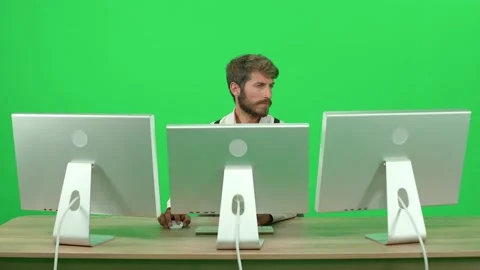 Software developer working on a PC while sitting at a desk, green background, a Stock Footage 239629671