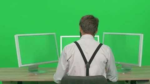 Software developer working on a PC while sitting at a desk, green background Stock Footage 243348930