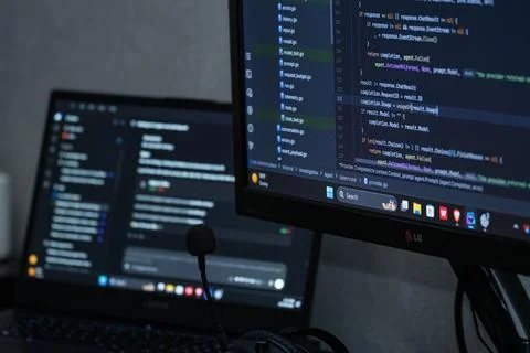 Software developer workspace with code on monitor screens 스톡 사진