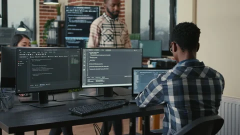 Software developer writing code on laptop and computer keyboard looking at Stock Footage 168253438