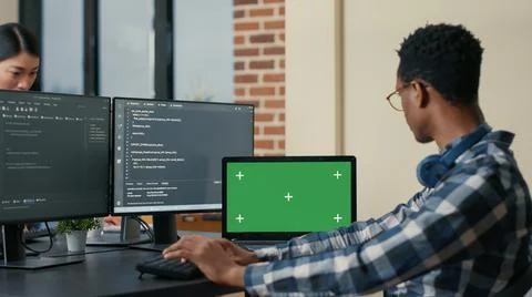 Software developer writing code using computer keyboard and laptop with green Stock Photos