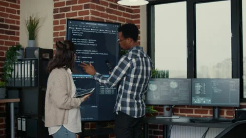 Software developers analyzing source code on wall screen tv comparing errors Stock Footage 168249769