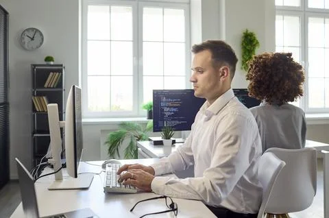 Software developers coding at computers in modern office, teamwork focus today Stock Photos