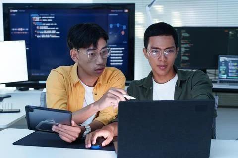 Software Developers Collaborating on Code with Laptop and Tablet Fotos Stock