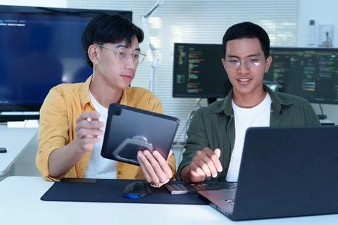 Software developers collaborating with tablet and laptop in modern office Stock Photos