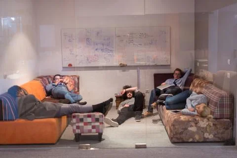 Software developers sleeping on sofa in creative startup office 스톡 사진