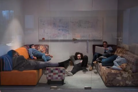 Software developers sleeping on sofa in creative startup office 스톡 사진