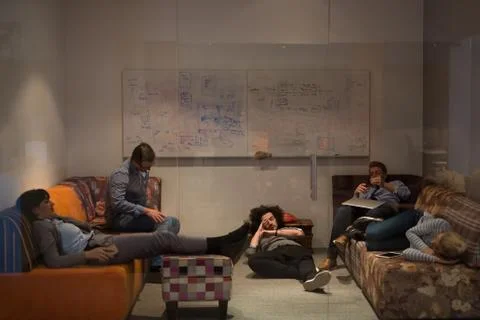 Software developers sleeping on sofa in creative startup office 스톡 사진