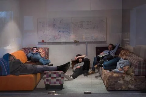 Software developers sleeping on sofa in creative startup office group of y... 스톡 사진