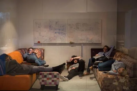 Software developers sleeping on sofa in creative startup office group of y... 스톡 사진