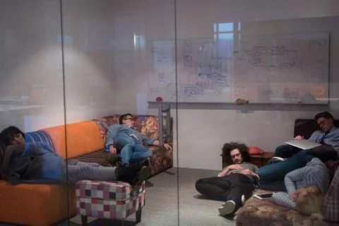 Software developers sleeping on sofa in creative startup office group of y... 스톡 사진