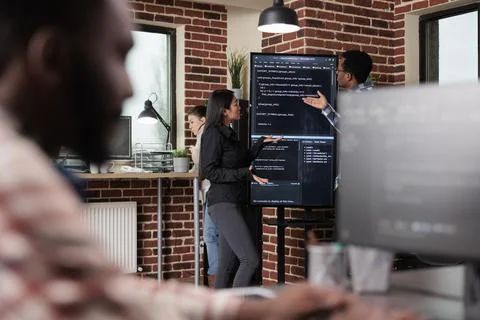 Software developers standing near vertical screen talking about interface bug Stock Photos