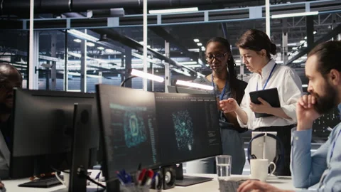 Software developers working together in server farm, reviewing AI code Video stock 309631141