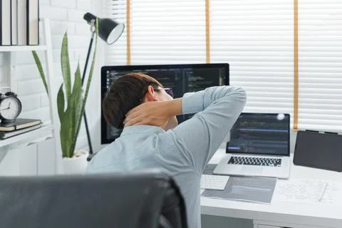 Software development concept, Male programmer suffering neck pain after worki Stockfoto's