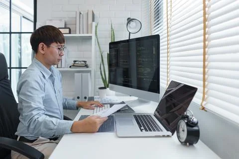 Software development concept, Male programmer read data on document while pro 스톡 사진