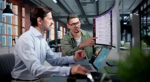 Software Engineer And Colleague Test AI Chatbot On Ultrawide Curved Monitor T Stock Photos