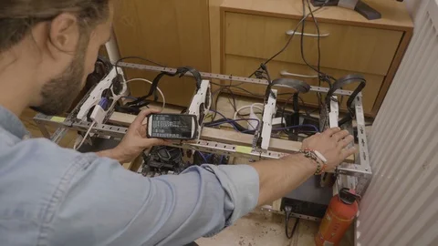 Software engineer checking connections of cryptocurrency rig and tracking pro Stock Footage 102473957
