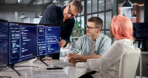 Software Engineer Coding On Computer While Collaborating With Diverse Team. Stock Photos
