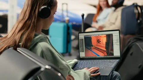Software engineer creating gaming assets for video game in the airport lounge Stock Footage 333172968